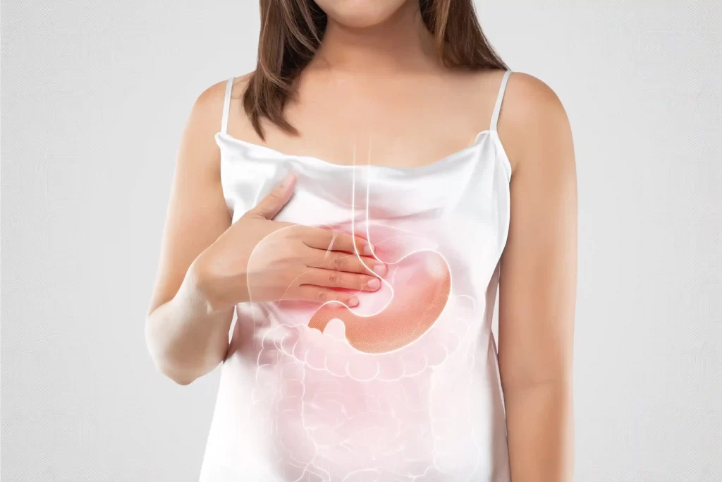 Cardápio para Refluxo: café da manhã, almoço e jantar 6 Mulher com desconforto estomacal segurando a barriga, indicando sintomas de refluxo emocional